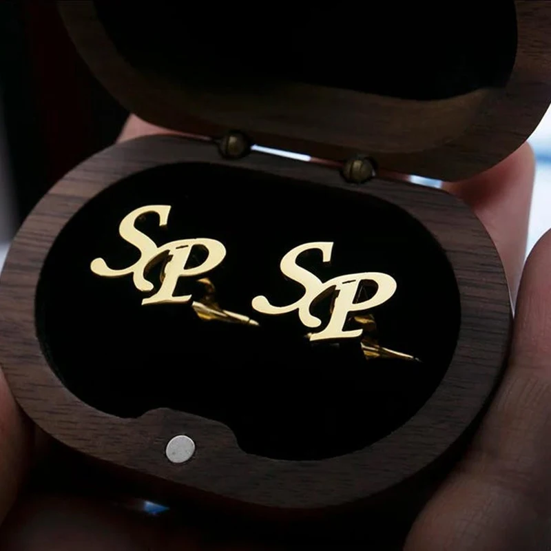 Gold cufflinks with 'SP' initials in a wooden box