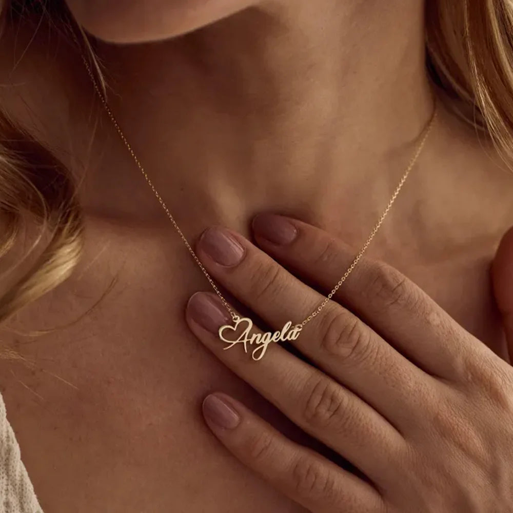 Gold necklace with 'Angela' pendant worn by a person, close-up on skin.