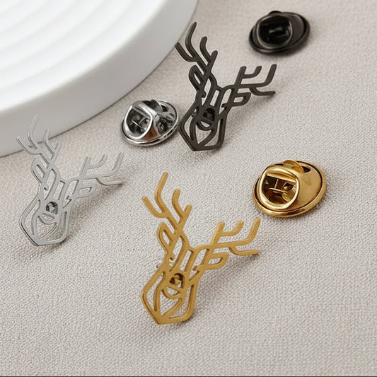 Four deer-shaped pins in gold, silver, and black on a light gray surface.