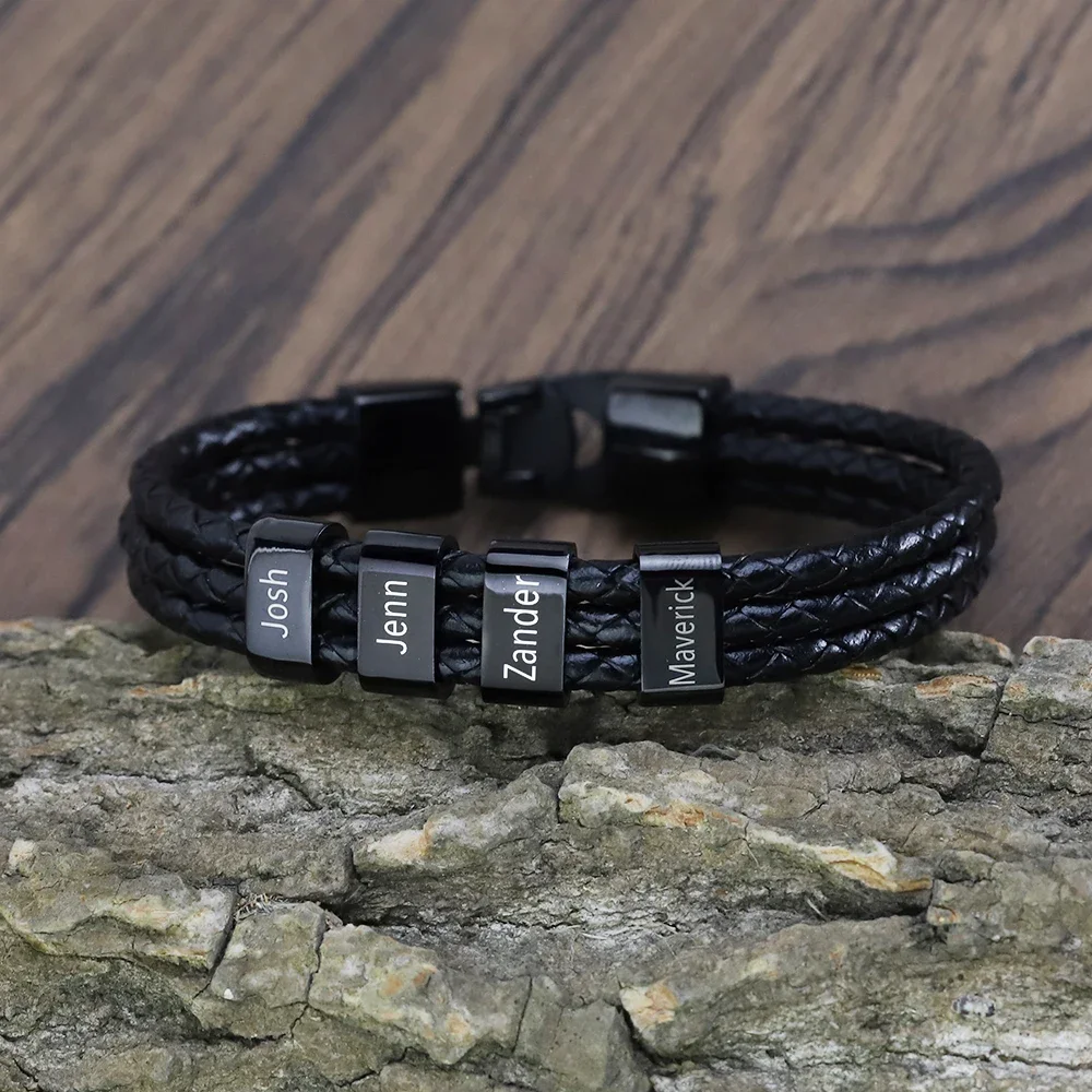 Black leather bracelet with engraved name tags on a wooden surface