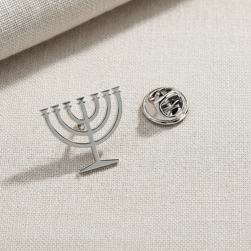 Silver Menorah-shaped lapel pin on a light fabric background
