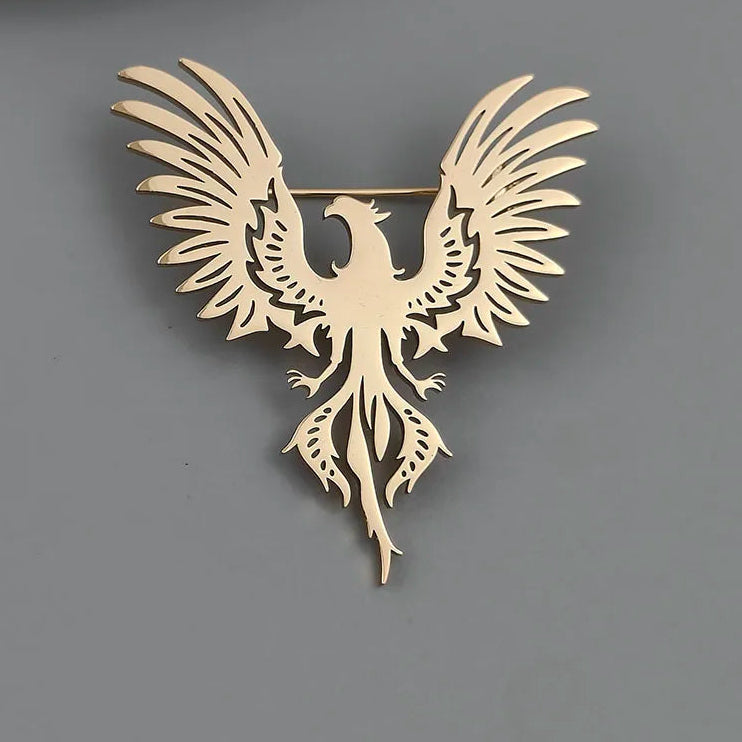 Gold phoenix brooch on a gray surface