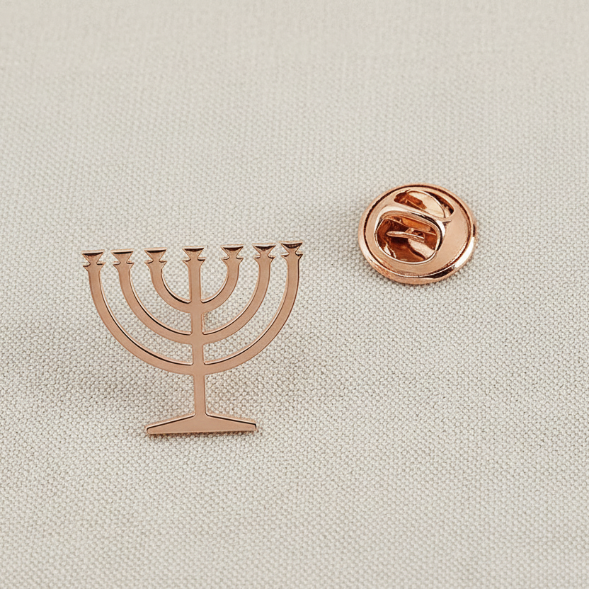 Rose gold menorah-shaped lapel pin on a light beige background