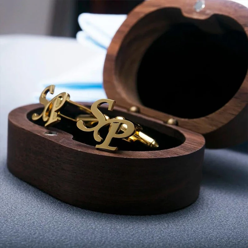 Wooden box with 'DR' initials and a pair of earrings inside, held by a hand.

