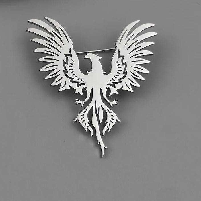 Silver phoenix brooch on a gray surface
