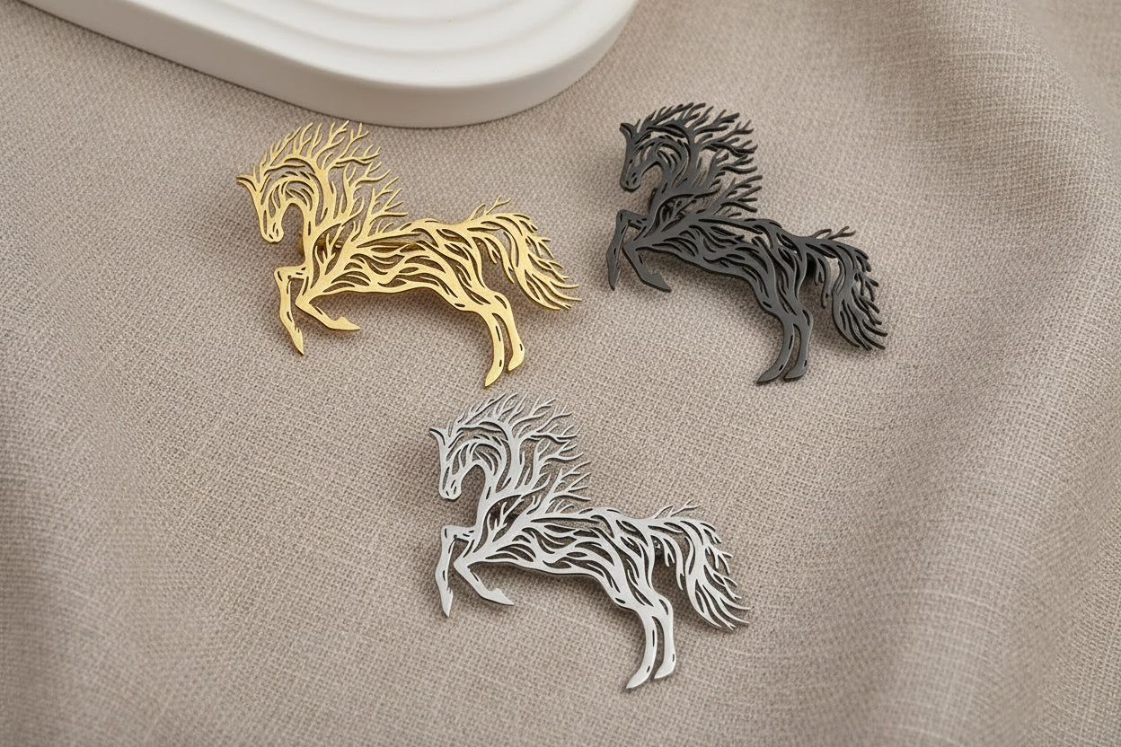 Three horse-shaped decorative items in gold, silver, and black on a gray background.