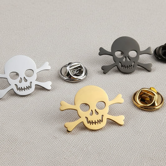 A set of stainless steel Viking cross skull brooches in silver, gold, and black colors, displayed on a white surface.