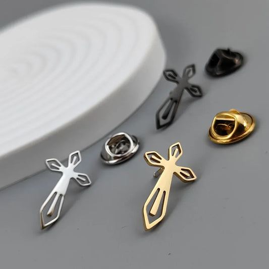 A set of stainless steel cross brooches for men, displayed in silver, gold, and black colors, presented on a white surface.
