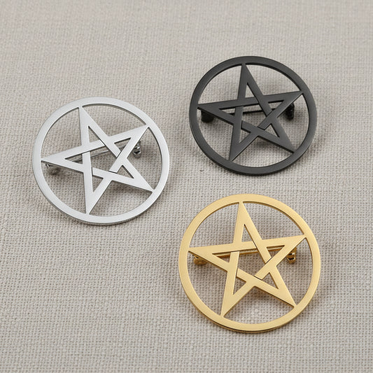 Three pentagram-shaped objects in silver, gold, and black on a gray surface.