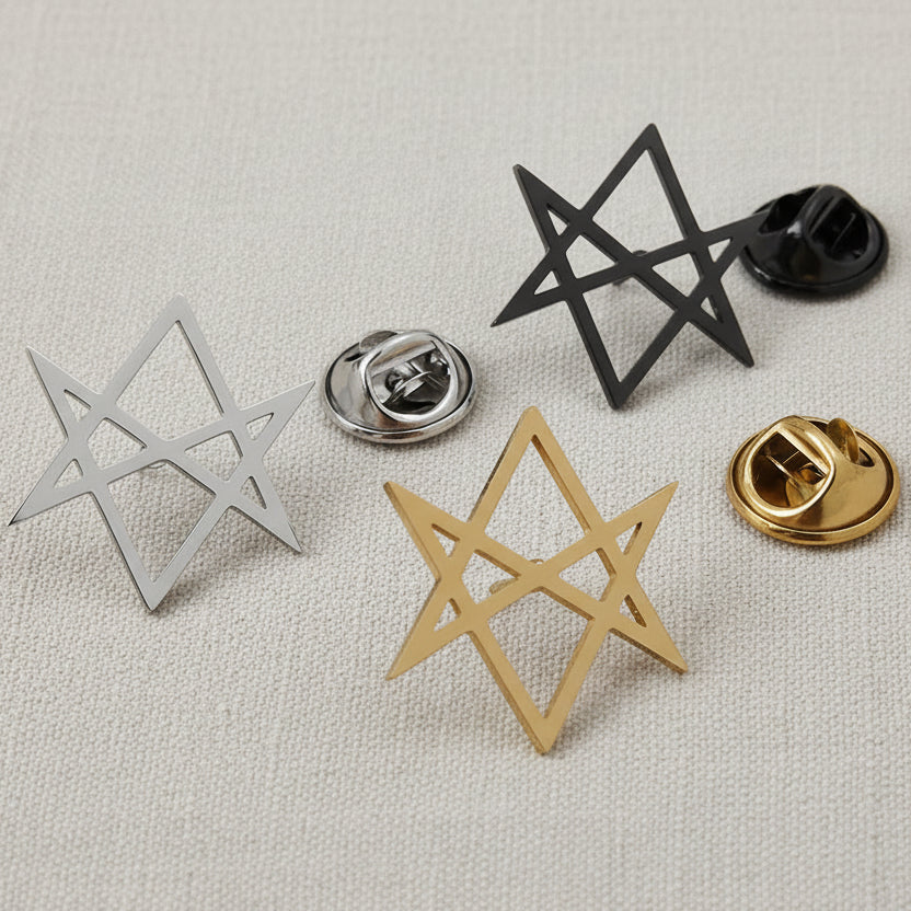 A collection of geometric-shaped brooches in silver and gold colors displayed on a grey surface.