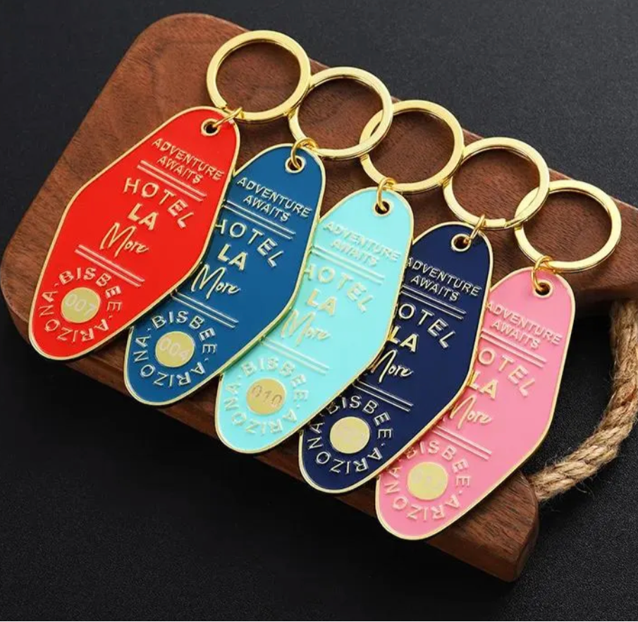Set of colorful custom logo enamel keychains on a wooden stand.