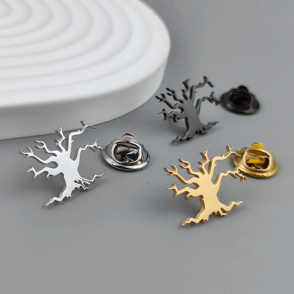 A set of Tree of Life-shaped brooches in silver and gold colors, displayed on a white surface.