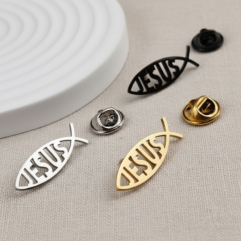 Metallic 'Jesus' fish pins on a beige surface with a white circular object.