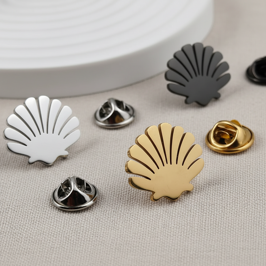 Gold shell-shaped brooch pin on a gray surface with other shell pins in the background.